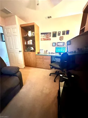 Office space featuring light carpet and built in study area