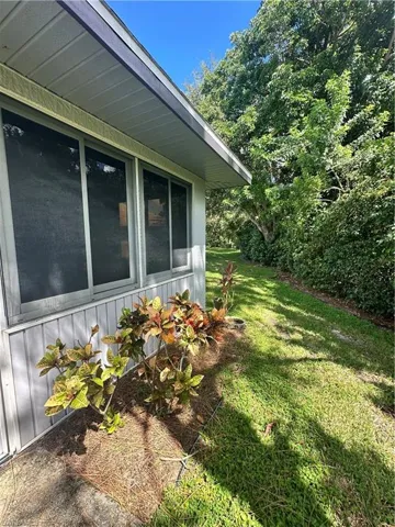 View of property exterior with a yard and a sunroom