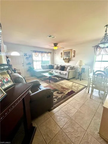 Living room with light tile patterned floors, healthy amount of natural light, and a ceiling fan