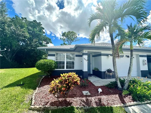 View of front of home featuring an attached garage, stucco siding, and a front yard