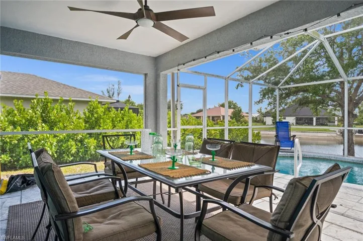 Sunroom featuring outdoor dining space, a ceiling fan, a water view, and a patio