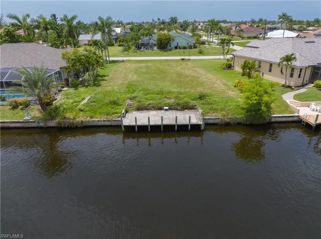 Rear view of house featuring a pool, a water view, and a yard