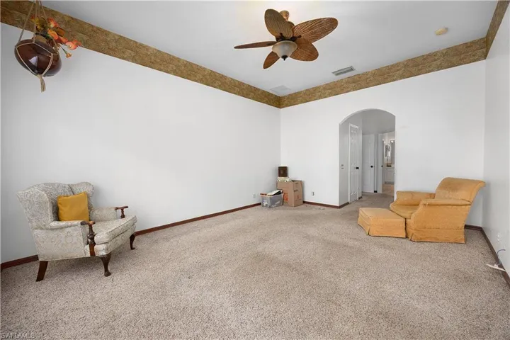 Unfurnished room with arched walkways, carpet, and a ceiling fan