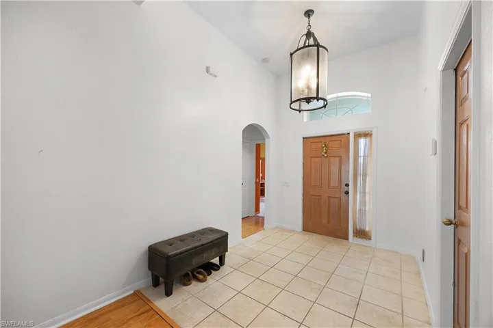 Foyer entrance with arched walkways, a high ceiling, and light tile patterned floors