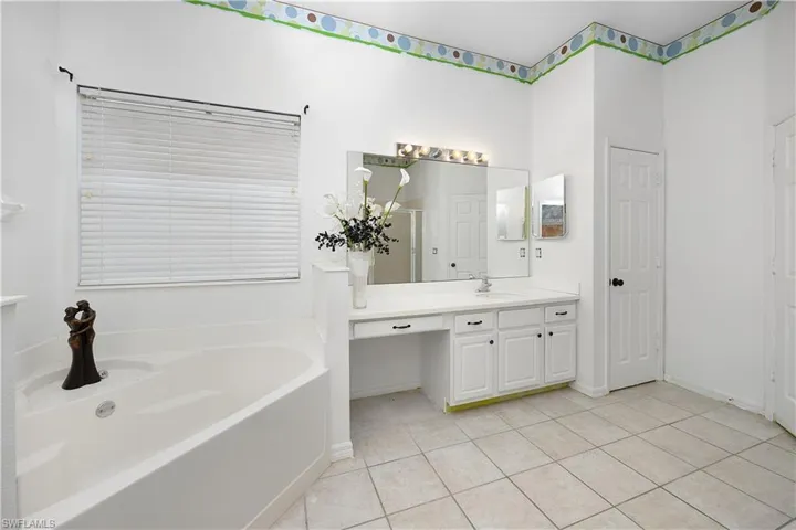 Full bath featuring a bath, vanity, light tile patterned flooring, and a shower stall