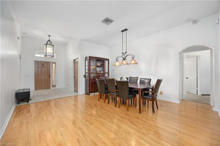 Dining space featuring a chandelier, arched walkways, and light wood-type flooring