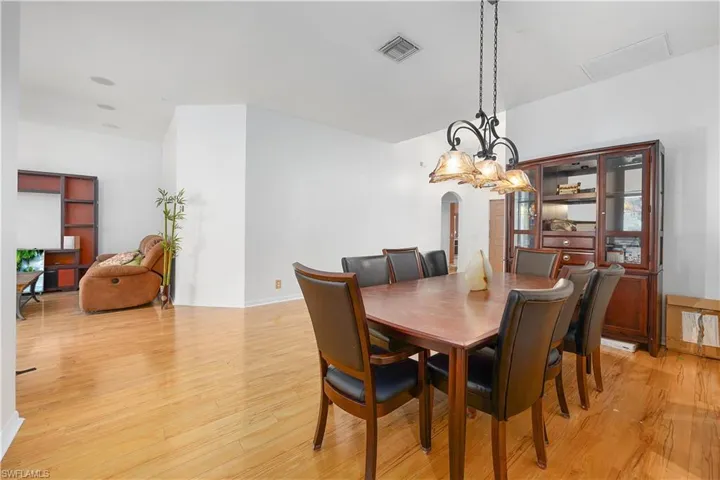 Dining space featuring arched walkways and light wood-style flooring