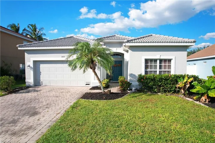 View of front of house with a tile roof, decorative driveway, stucco siding, and a front yard