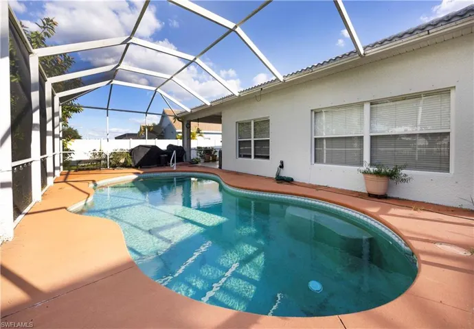 Outdoor pool featuring glass enclosure, a sunroom, and a patio