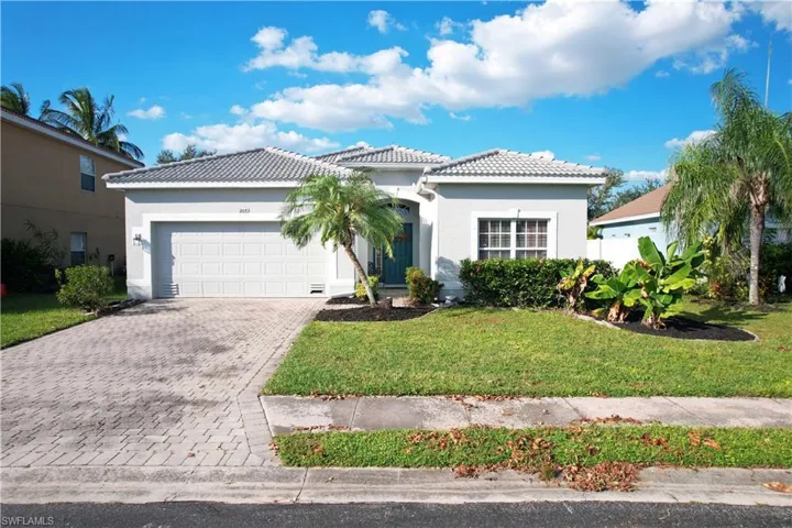 View of front of property featuring decorative driveway, stucco siding, a tiled roof, a garage, and a front lawn