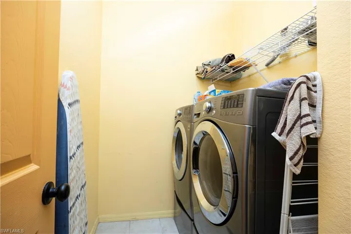 Laundry room with washing machine and dryer and light tile patterned flooring