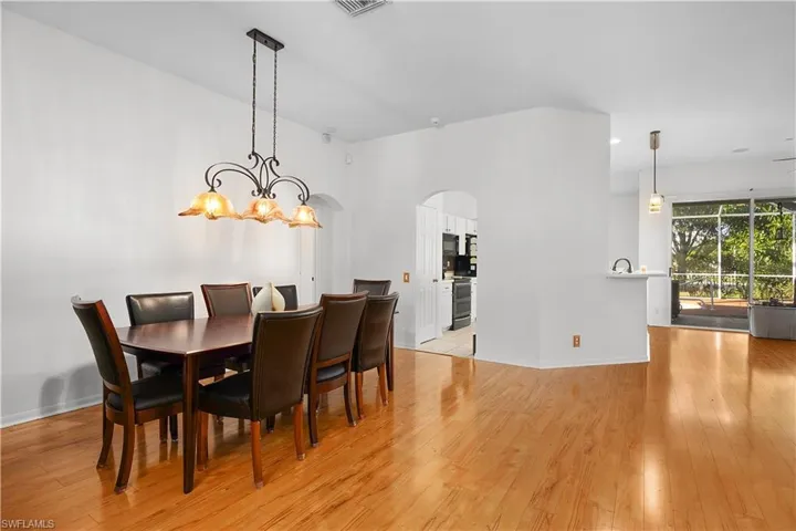 Dining room with a chandelier, light wood finished floors, arched walkways, and recessed lighting