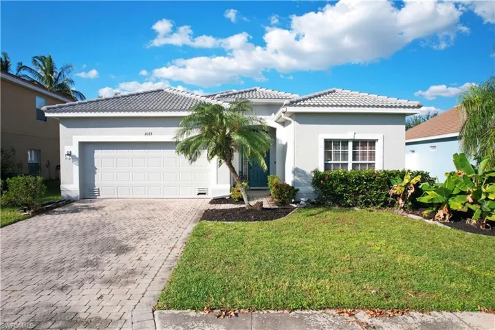 View of front facade with a tile roof, stucco siding, decorative driveway, a garage, and a front yard
