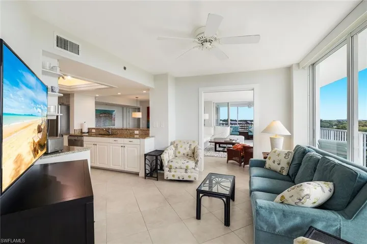Living area featuring a ceiling fan, light tile patterned floors, and a tray ceiling