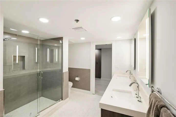 Bathroom featuring double vanity, recessed lighting, and a shower stall
