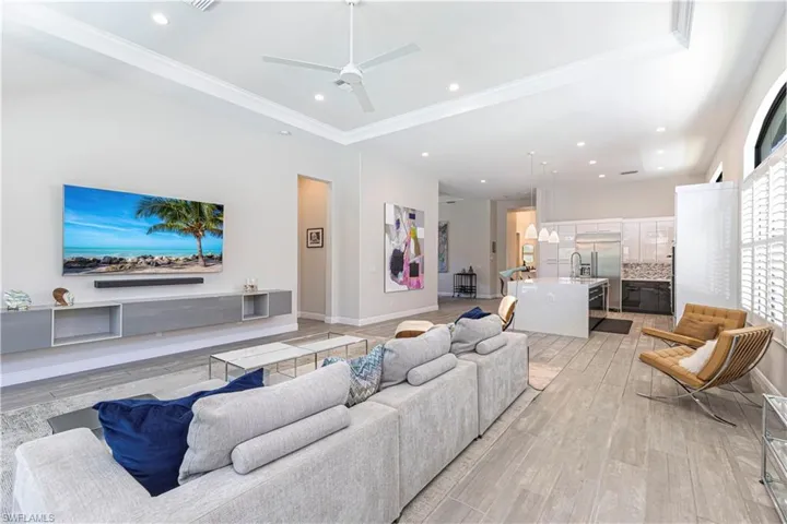 Living room with ceiling fan, ornamental molding, light wood-style flooring, recessed lighting, and baseboards