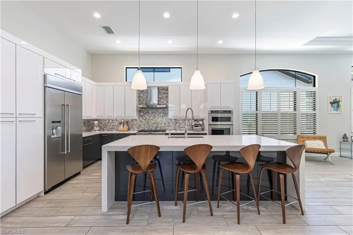 Kitchen featuring stainless steel appliances, wall chimney exhaust hood, backsplash, recessed lighting, and quartz countertops