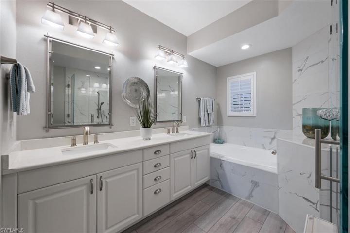 Primary bathroom with double sinks, white and bright and beautiful quartz veins throughout bathroom stone.