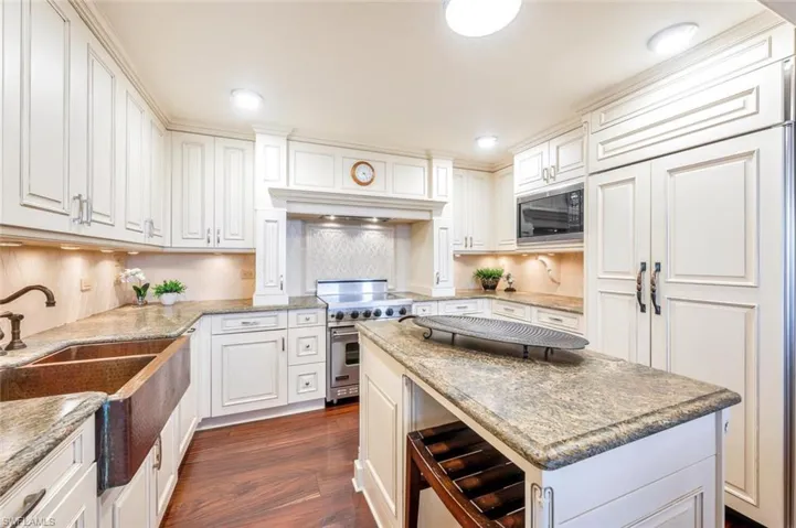 Kitchen featuring dark hardwood / wood-style flooring, high end range, white cabinetry, wine cooler, and black microwave