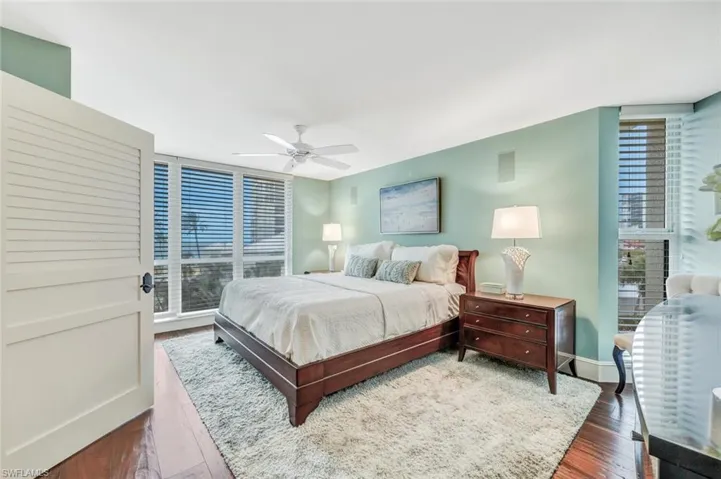 Bedroom featuring ceiling fan, multiple windows, and dark hardwood / wood-style flooring