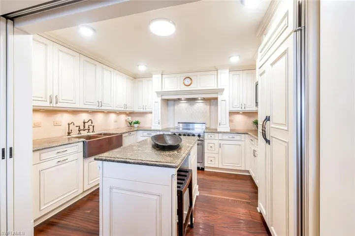 Kitchen featuring white cabinets, a center island, stainless steel range, and dark hardwood / wood-style flooring