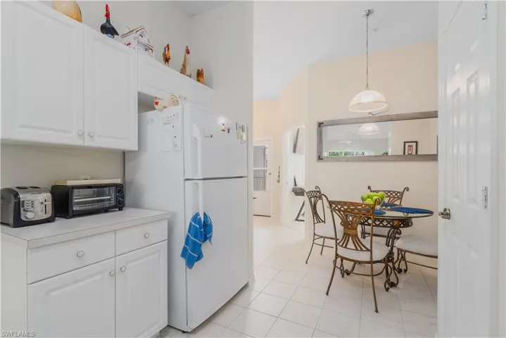 Kitchen featuring pendant lighting, white refrigerator, light tile patterned floors, and white cabinetry