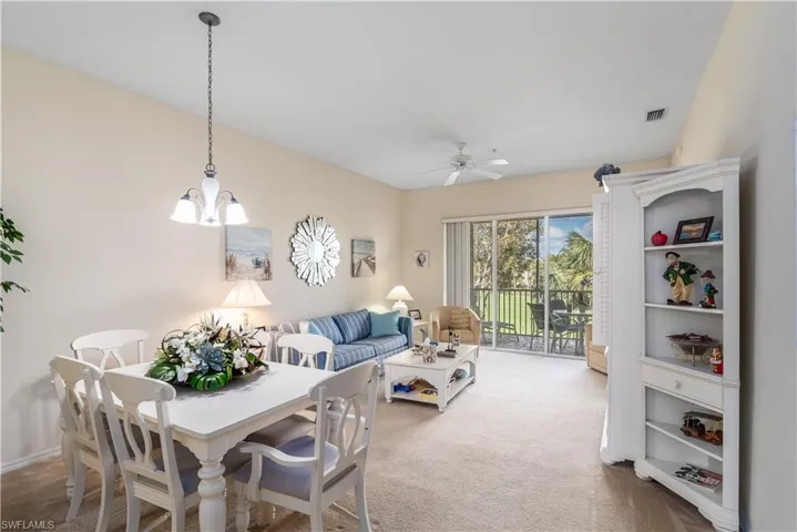 Carpeted dining room with ceiling fan with notable chandelier