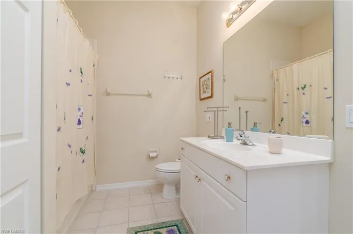 Bathroom featuring tile patterned flooring, vanity, toilet, and a shower with curtain