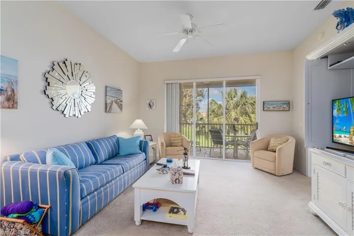 Carpeted living room featuring ceiling fan