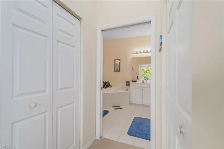 Bathroom featuring vanity, tile patterned flooring, and a relaxing tiled tub
