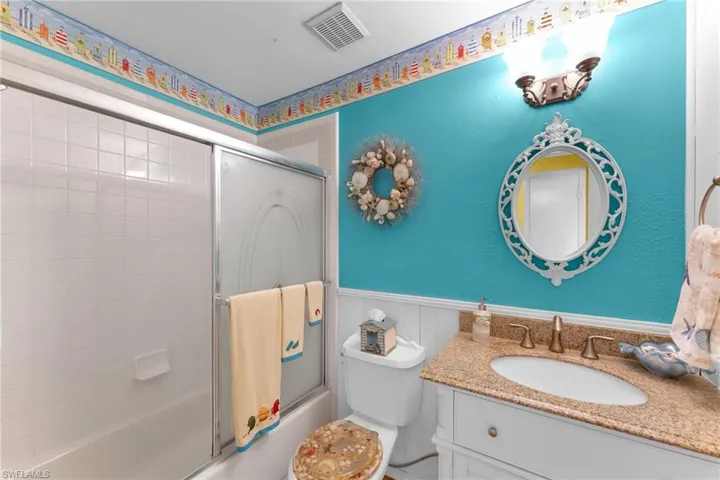 Full bathroom featuring vanity, bath / shower combo with glass door, and toilet