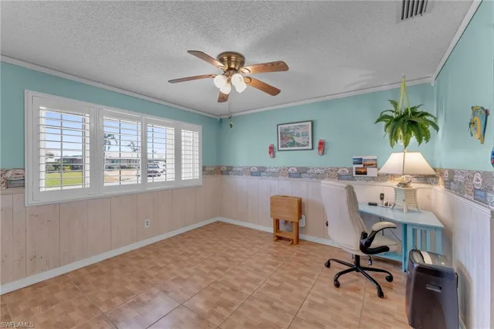 Office space featuring crown molding, ceiling fan, and a textured ceiling