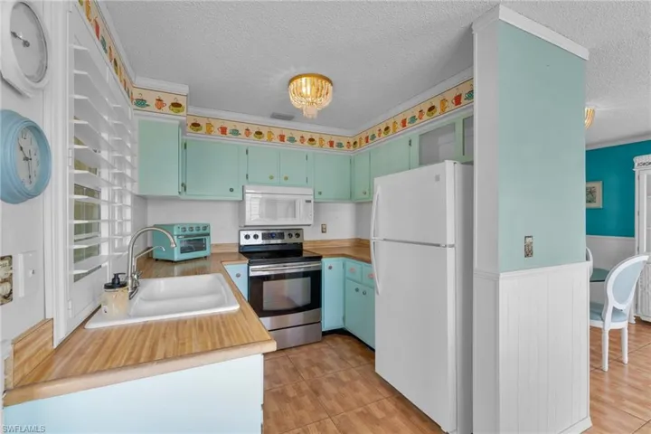 Kitchen featuring white appliances, sink, a textured ceiling, and light tile patterned floors