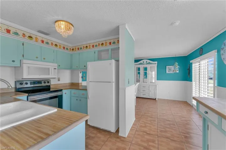 Kitchen with crown molding, light tile patterned floors, white appliances, and a textured ceiling