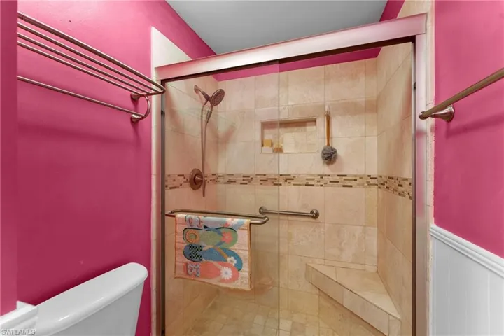 Bathroom featuring a shower with door and toilet