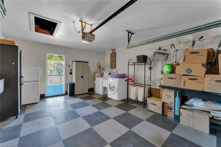 Garage with a garage door opener, electric panel, and washing machine and clothes dryer