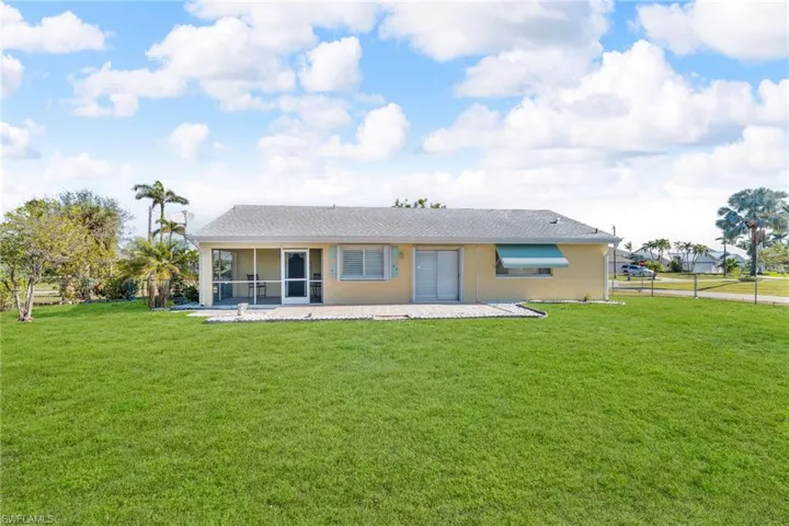 Rear view of property featuring a sunroom and a lawn