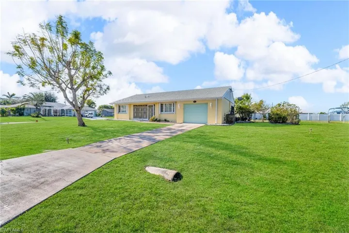 Ranch-style house with a garage and a front lawn