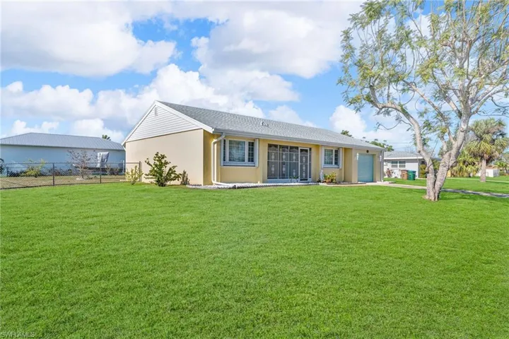 Rear view of property with a garage and a yard