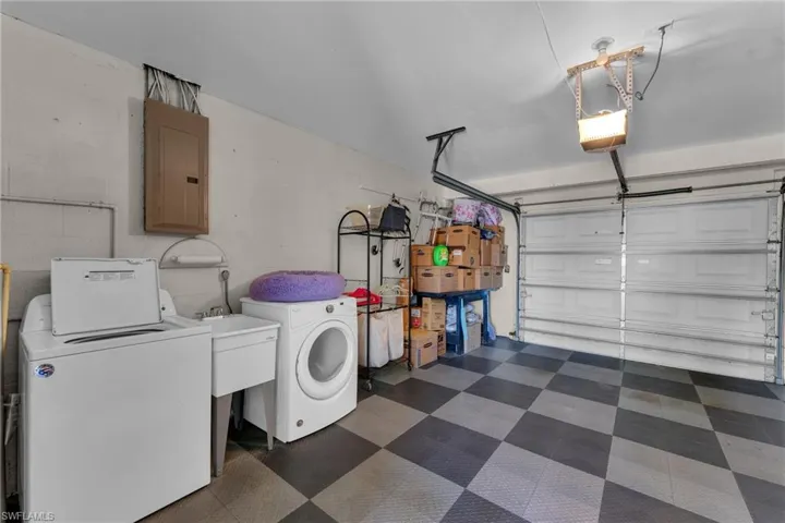 Garage with a garage door opener, washer and clothes dryer, and electric panel
