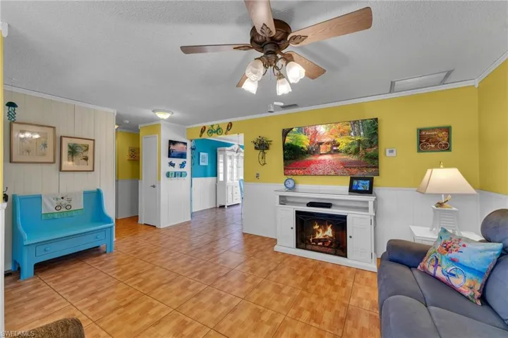 Living room with ornamental molding, a textured ceiling, and light tile patterned flooring