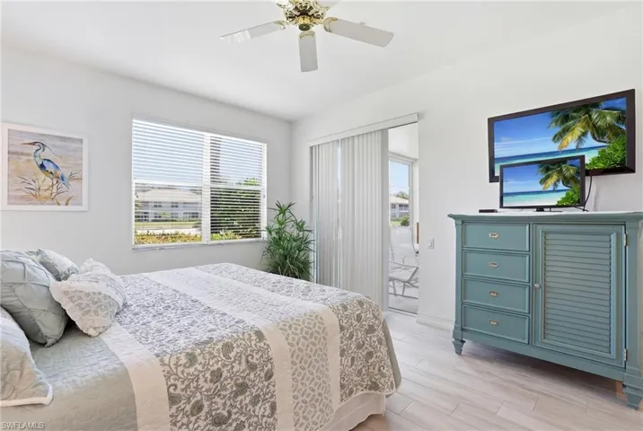 Bright interior with a ceiling fan, white window blinds, light wood-finish flooring, and a sliding glass door opening to an exterior patio