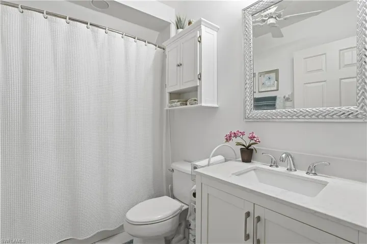 Bathroom with a white vanity featuring a rectangular undermount sink, a polished chrome widespread faucet, and a light-colored countertop
