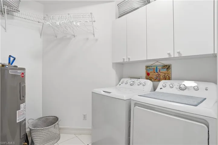 Dedicated laundry area featuring white upper cabinetry, wire shelving, and a water heater