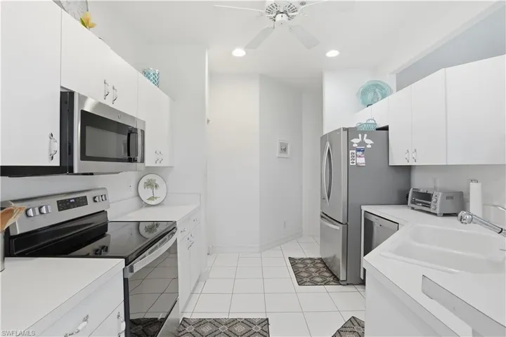 Kitchen featuring white cabinetry, white countertops, stainless steel appliances, a white ceiling fan, and recessed lighting