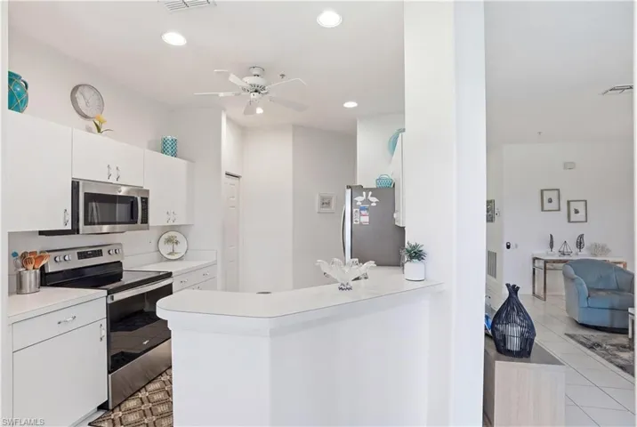 Kitchen featuring white cabinetry, stainless steel microwave, and a black and stainless steel range