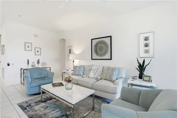 Spacious living area featuring white tile flooring, neutral wall tones, and a recessed archway