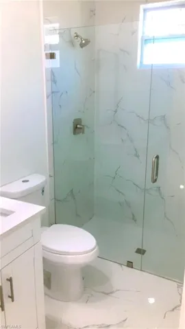 Guest bathroom featuring vanity, an enclosed shower, tile patterned flooring, and toilet