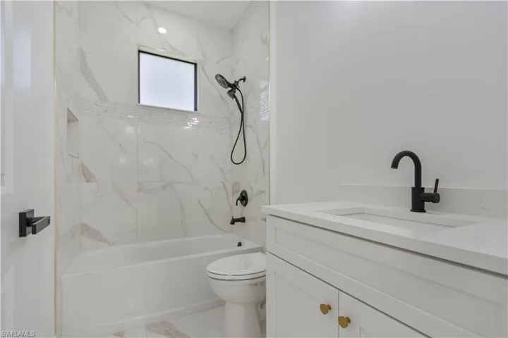 Bathroom with vanity, toilet, shower / washtub combination, and marble finish flooring