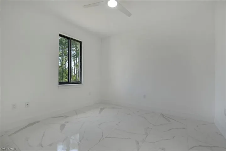 Unfurnished room featuring baseboards, ceiling fan, and light marble finish flooring